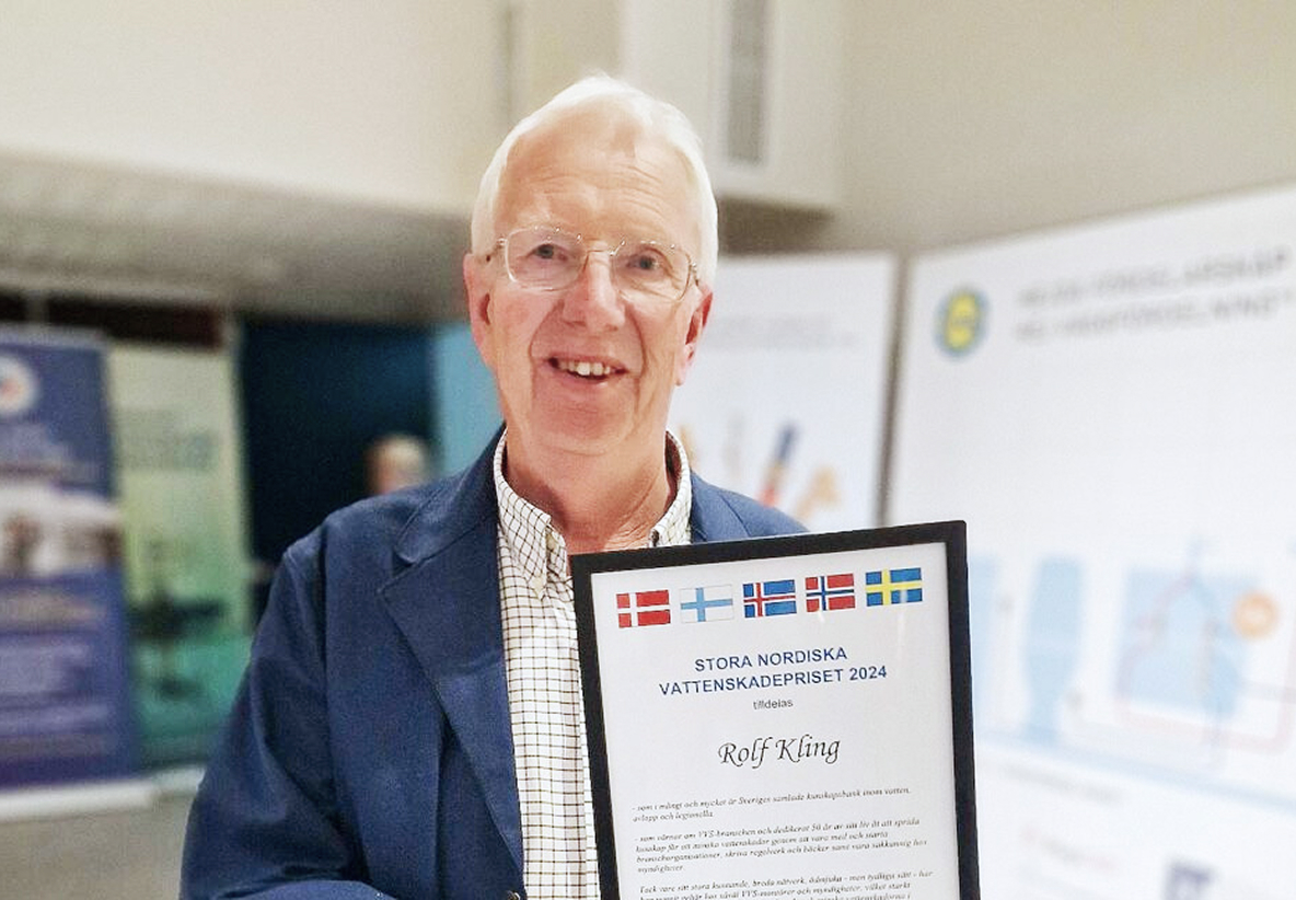 Äldre man med glasögon ler och håller ett diplom med texten "Stora Nordiska Vattenskadepriset 2024". Han är vinnaren av vattenskadepriset 2024.