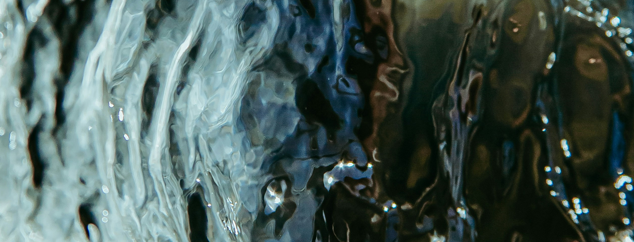 Närbild av rinnande vatten med reflektioner och ljusspel.