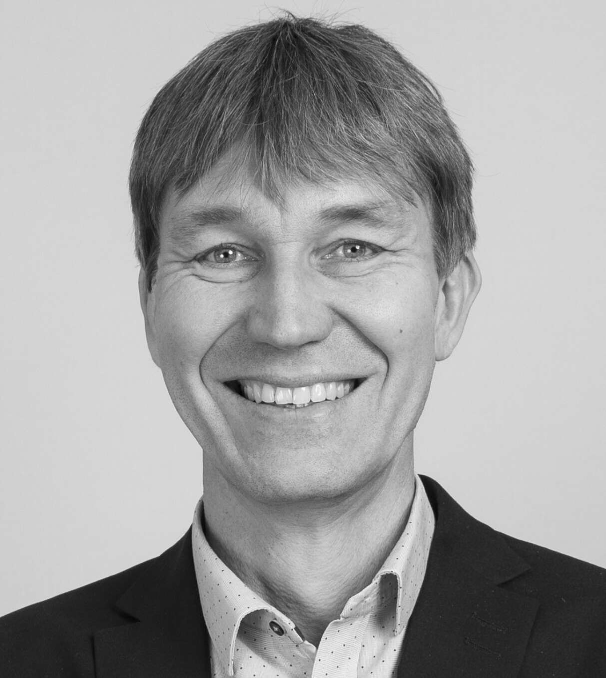 Svartvit bild på leende man i skjorta och kostym