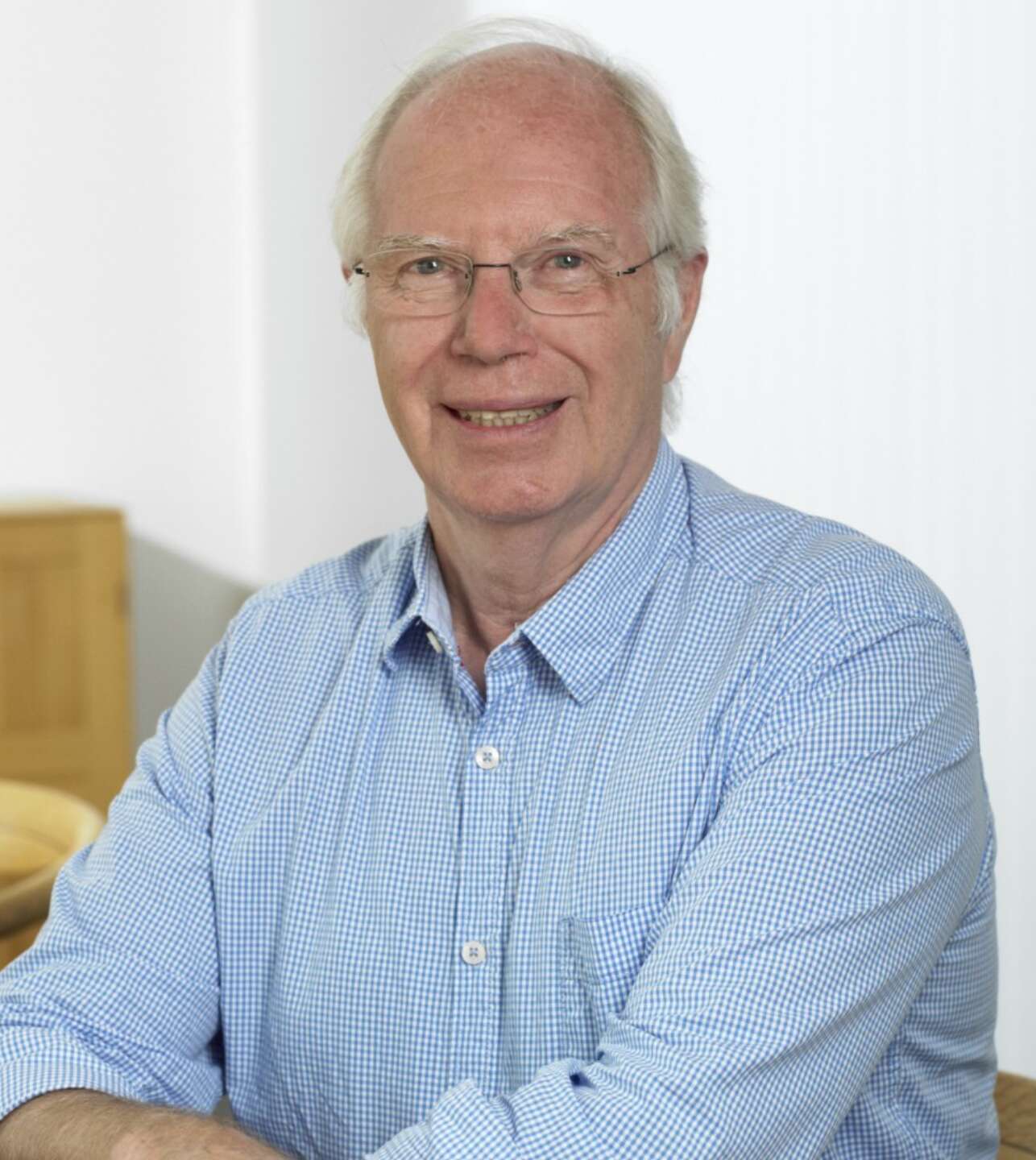 Leende äldre man med glasögon och blå vit skjorta